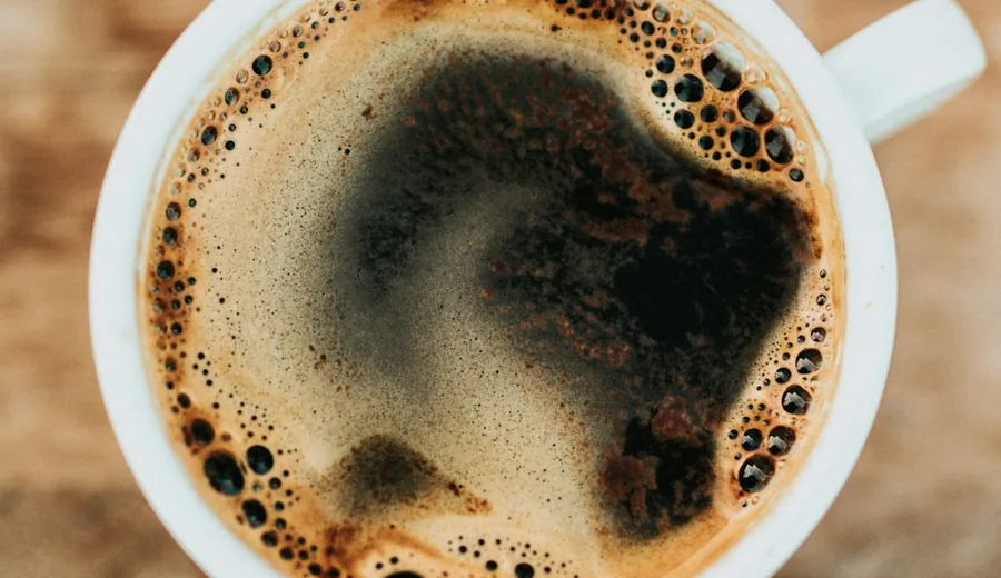Freshly brewed cup of black coffee and a glass of mineral water with lemon