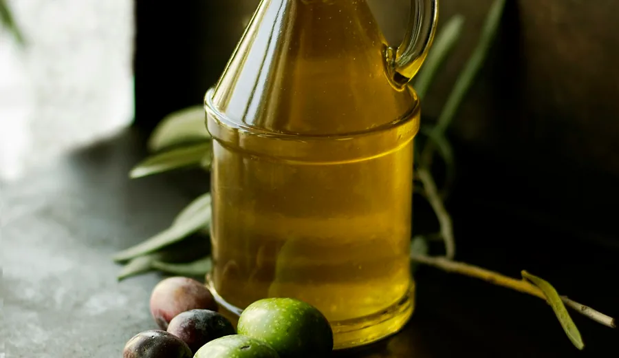 Cold-pressed extra virgin olive oil poured from a glass cruet into a ceramic dish