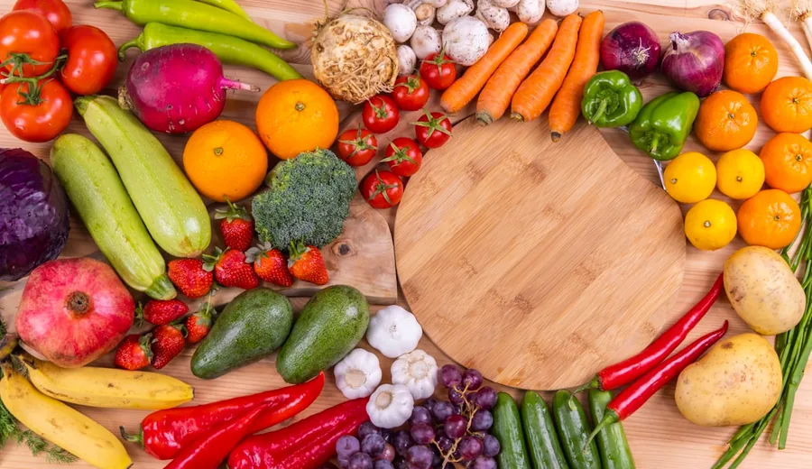Basket filled with fresh whole foods including greens, root vegetables, citrus, and whole grains