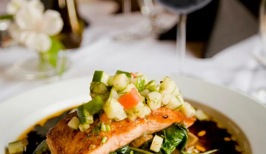 Pan-seared salmon fillet served with roasted asparagus, sweet potatoes, and fresh lemon