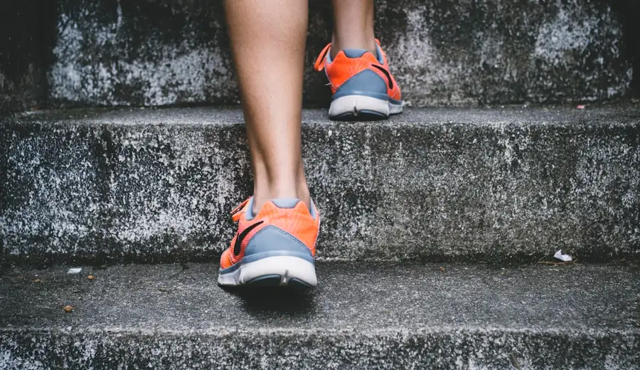 Person walking briskly outdoors in athletic shoes illustrating daily NEAT energy expenditure